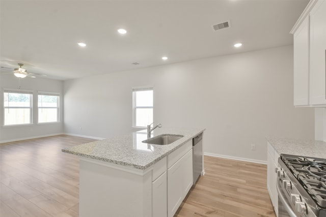 kitchen with white cabinetry, light wood-type flooring, sink, and an island with sink