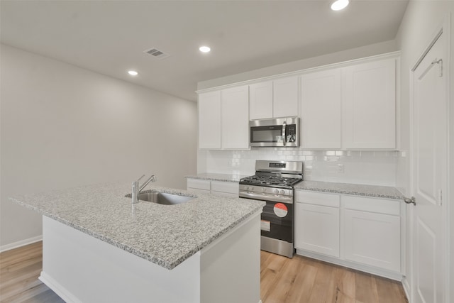 kitchen featuring white cabinetry, appliances with stainless steel finishes, sink, and a kitchen island with sink