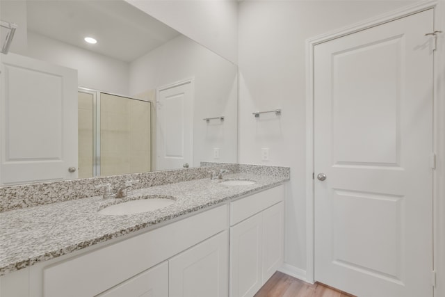 bathroom with hardwood / wood-style flooring, a shower with door, and vanity