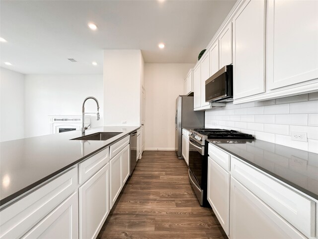 kitchen with stainless steel appliances, white cabinetry, sink, dark hardwood / wood-style flooring, and decorative backsplash