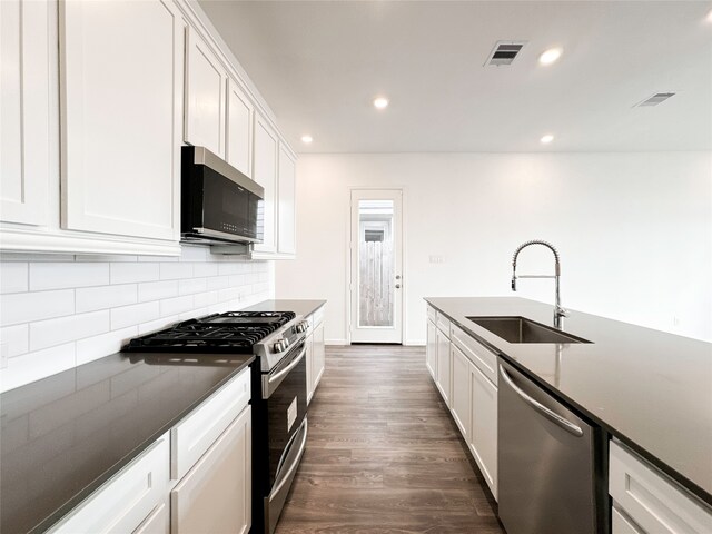 kitchen with stainless steel appliances, sink, tasteful backsplash, dark hardwood / wood-style floors, and white cabinets