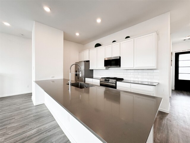 kitchen with kitchen peninsula, appliances with stainless steel finishes, hardwood / wood-style floors, and white cabinets