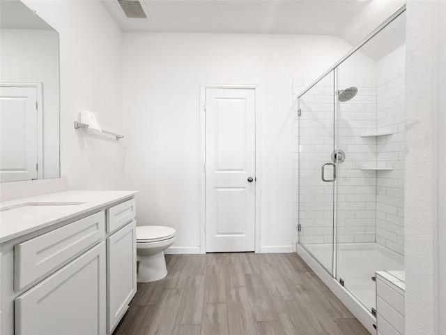 bathroom featuring hardwood / wood-style flooring, a shower with door, vanity, and toilet