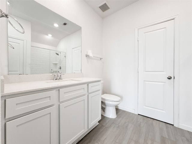 bathroom with hardwood / wood-style floors, a shower with shower door, vanity, and toilet