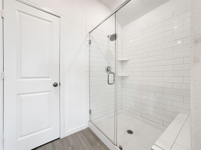 bathroom with wood-type flooring and a shower with shower door