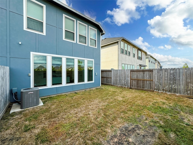 rear view of property with central AC and a yard