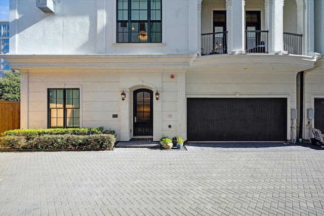 view of exterior entry with a balcony and a garage