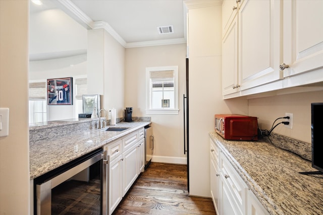 kitchen with ornamental molding, sink, wine cooler, dark hardwood / wood-style flooring, and light stone countertops