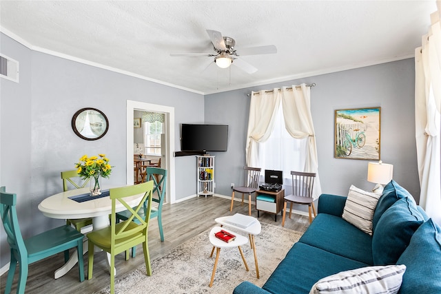 living room with ornamental molding, a textured ceiling, wood-type flooring, and ceiling fan