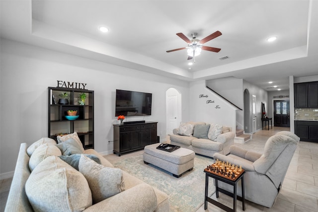 living room featuring ceiling fan and a tray ceiling