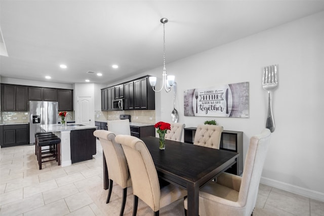 dining area with light tile patterned floors, sink, and a notable chandelier