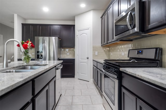 kitchen with stainless steel appliances, tasteful backsplash, sink, and light stone counters