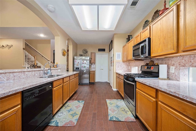 kitchen with stainless steel appliances, dark hardwood / wood-style flooring, light stone counters, sink, and tasteful backsplash