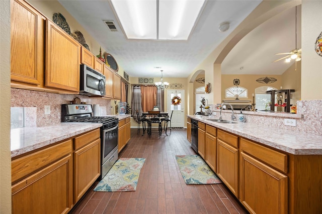 kitchen featuring stainless steel appliances, vaulted ceiling, sink, dark hardwood / wood-style floors, and decorative light fixtures