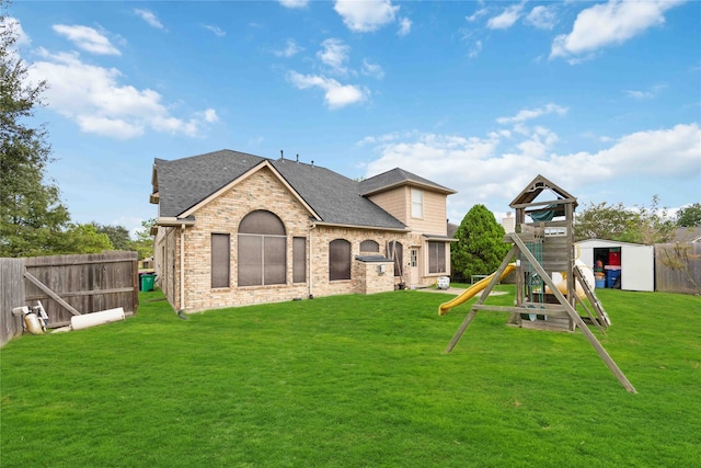 rear view of house with a lawn and a playground