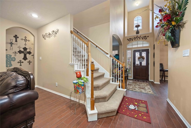 entryway with a high ceiling, a wealth of natural light, and dark hardwood / wood-style floors