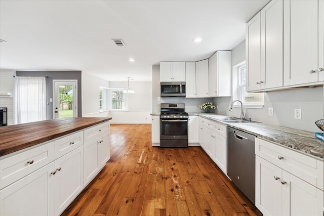 kitchen featuring white cabinets, appliances with stainless steel finishes, hardwood / wood-style flooring, and sink