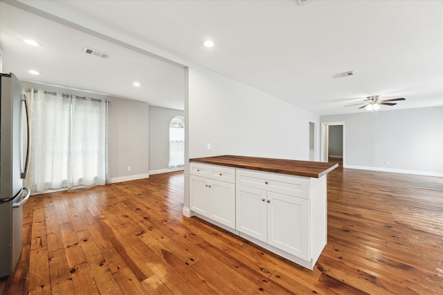 kitchen with butcher block counters, white cabinets, hardwood / wood-style floors, ceiling fan, and stainless steel refrigerator