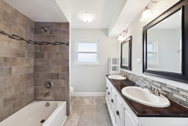 full bathroom featuring tasteful backsplash, vanity, tiled shower / bath combo, and toilet