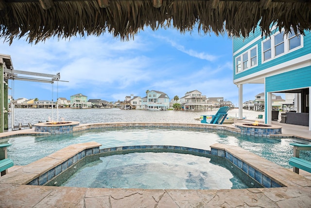 view of pool with pool water feature, a water view, and an in ground hot tub