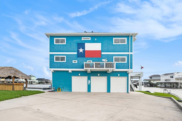 rear view of property featuring a water view, a garage, and a balcony