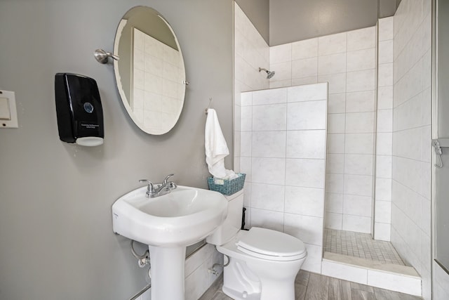 bathroom with a tile shower, hardwood / wood-style floors, and toilet