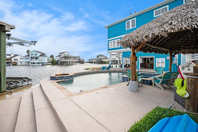 view of swimming pool with a water view, a patio, and a fire pit