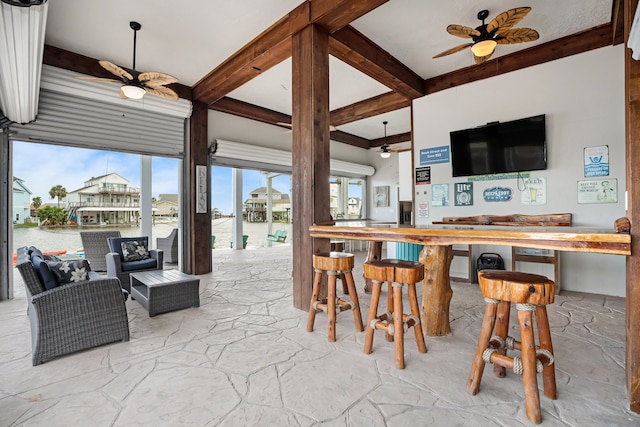 interior space featuring a bar, a water view, and ceiling fan