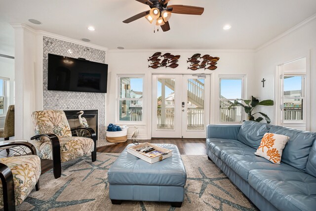 living room with a tiled fireplace, crown molding, french doors, and wood-type flooring