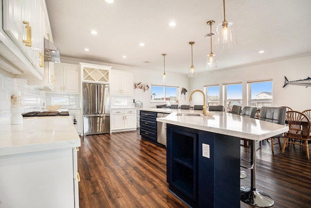 kitchen with a center island with sink, sink, hanging light fixtures, a kitchen bar, and stainless steel appliances