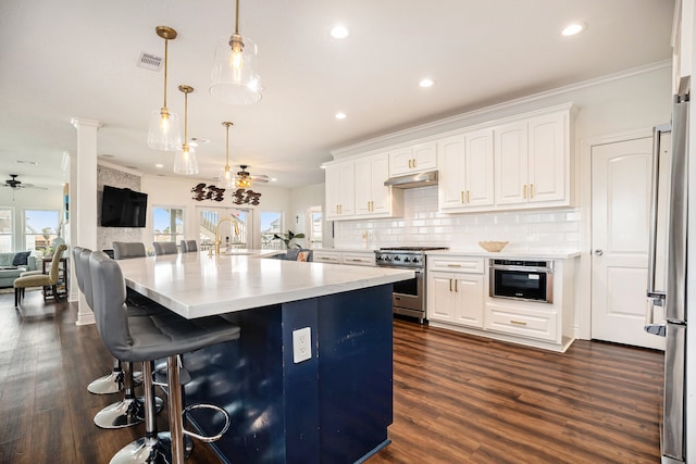 kitchen with pendant lighting, ceiling fan, plenty of natural light, white cabinetry, and stainless steel appliances