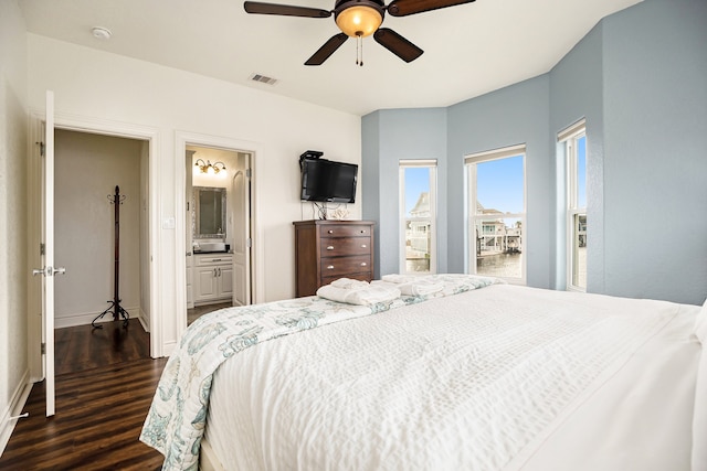 bedroom featuring dark hardwood / wood-style flooring, ensuite bathroom, and ceiling fan