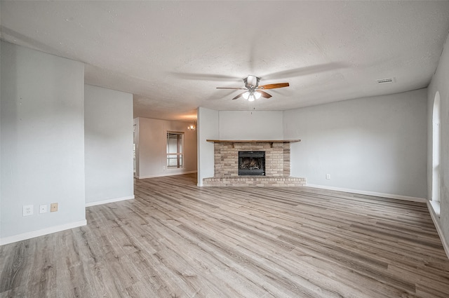 unfurnished living room featuring a fireplace, light hardwood / wood-style flooring, a textured ceiling, and ceiling fan