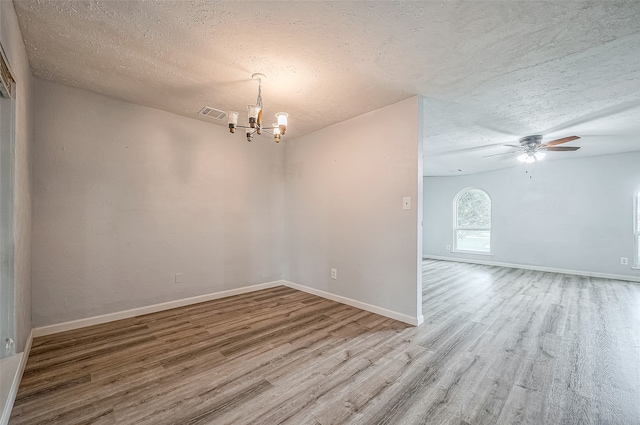 spare room with hardwood / wood-style flooring, ceiling fan with notable chandelier, and a textured ceiling