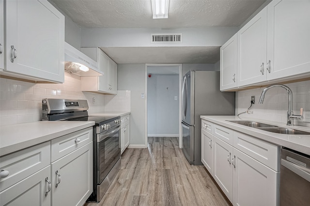 kitchen featuring stainless steel appliances, light hardwood / wood-style floors, sink, range hood, and white cabinets