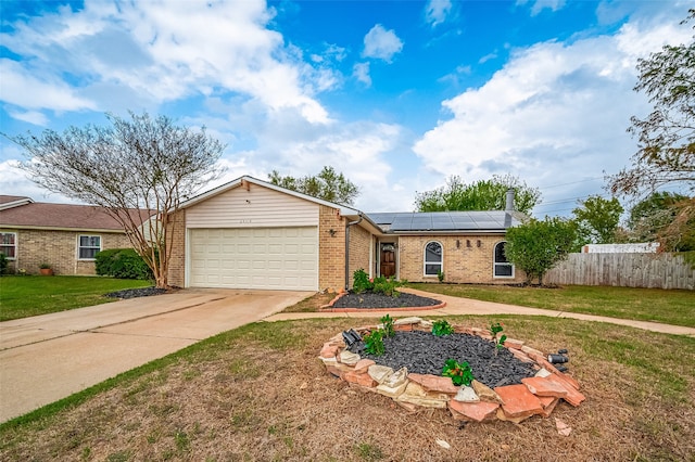 ranch-style home featuring solar panels, a front yard, and a garage