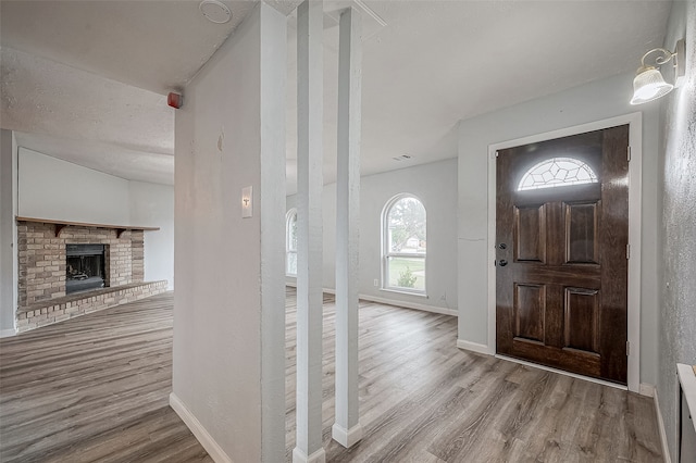 entryway with a brick fireplace and light hardwood / wood-style floors