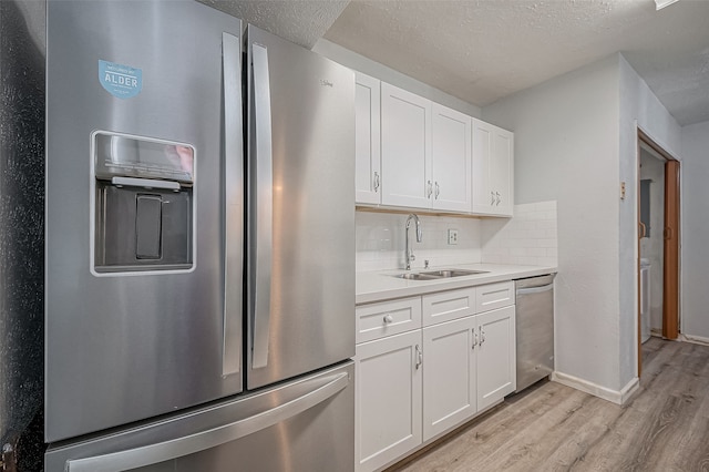 kitchen with white cabinetry, light hardwood / wood-style flooring, appliances with stainless steel finishes, and tasteful backsplash