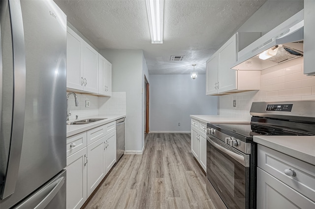 kitchen with stainless steel appliances, light hardwood / wood-style floors, white cabinets, sink, and range hood