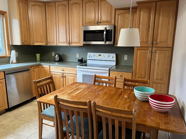 kitchen with decorative light fixtures, stainless steel appliances, and light tile patterned floors