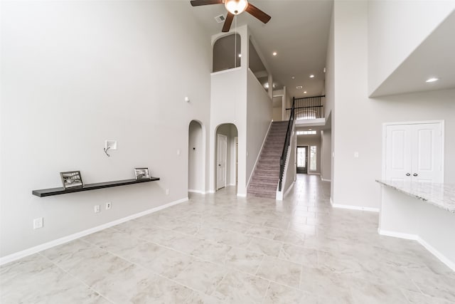 unfurnished living room featuring a high ceiling and ceiling fan