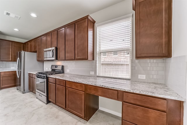 kitchen featuring tasteful backsplash, light stone countertops, and stainless steel appliances