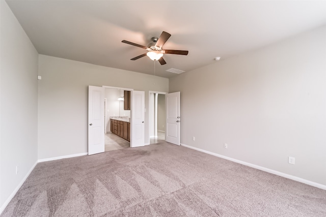 unfurnished bedroom with ceiling fan, ensuite bath, and light carpet