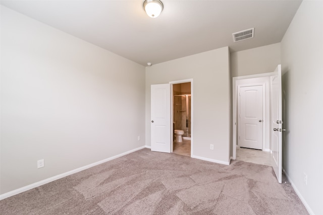 unfurnished bedroom with ensuite bath and light colored carpet