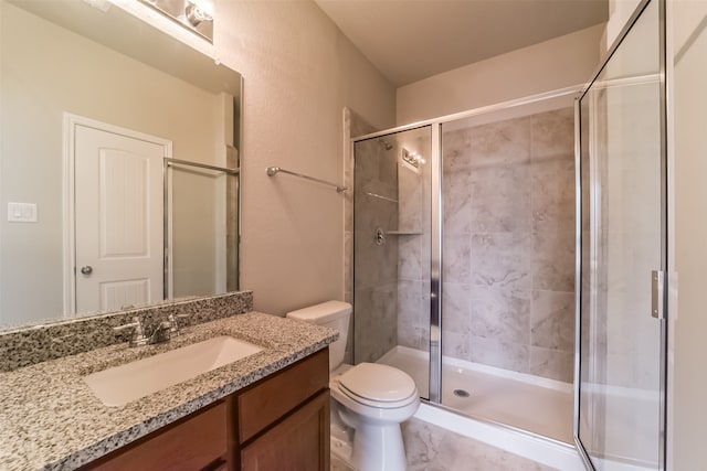 bathroom with toilet, vanity, and a shower with shower door