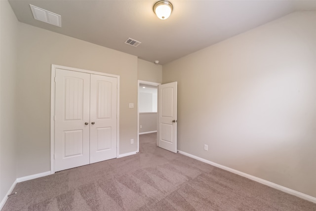 unfurnished bedroom with light colored carpet and a closet