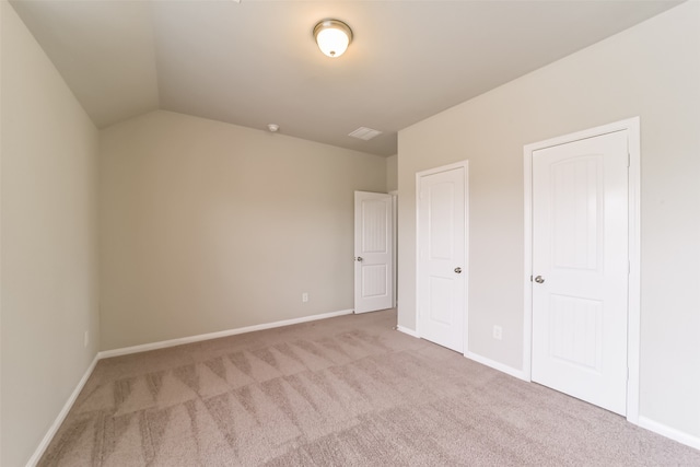 unfurnished bedroom featuring light colored carpet and vaulted ceiling