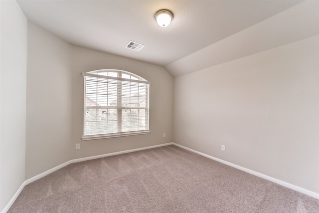 carpeted spare room with lofted ceiling