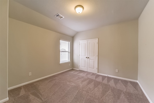 carpeted spare room featuring lofted ceiling