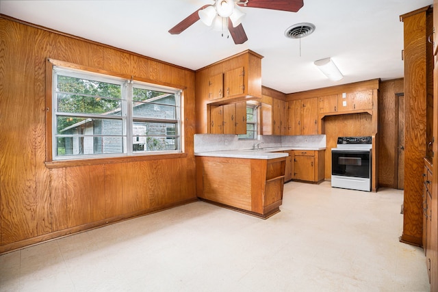 kitchen featuring wood walls, sink, electric range, kitchen peninsula, and ceiling fan